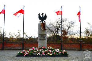 Pomnikiem Niepodległości w Strykowie, flagi narodowe, wiązanki kwiatów i znicze